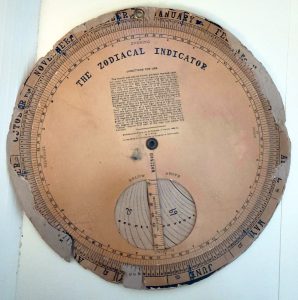 Zodiacal Indicator - A brown paper wheel which can be turned to display the position of different star signs at a specific time and date