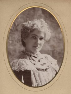 Photograph showing Jane Sousa, wearing a frilly white lace dress.