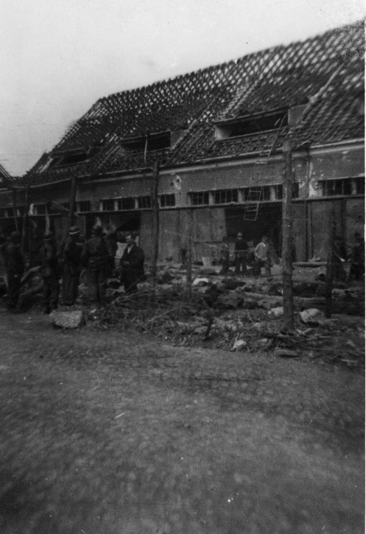 Prisoners and soldiers stand near rows of the dead in Dora-Mittelbau compound.